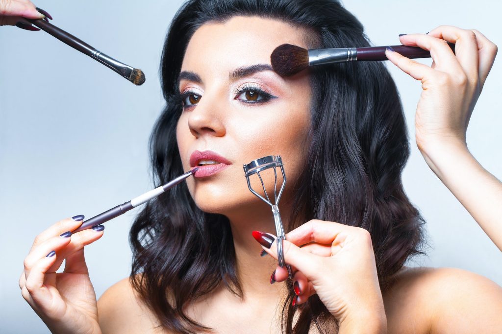 Close up of young woman face with all kinds of make up tools - brush, lipstick