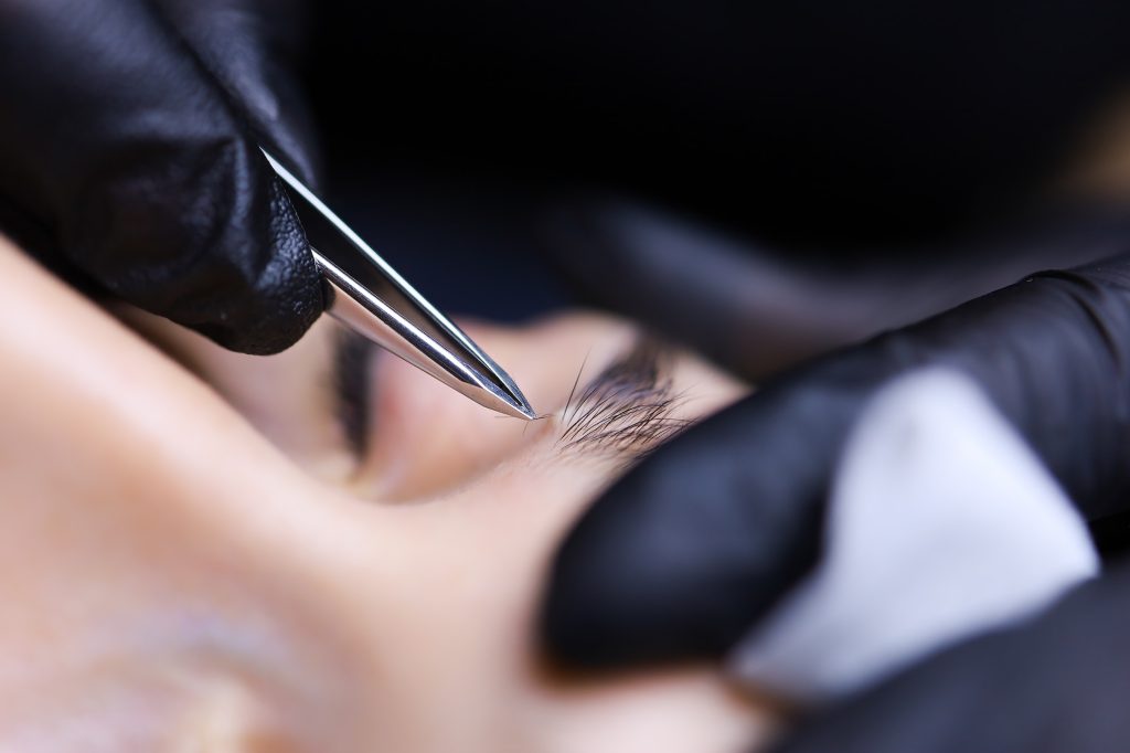 the master of permanent makeup prepares the client's eyebrows for the procedure plucking