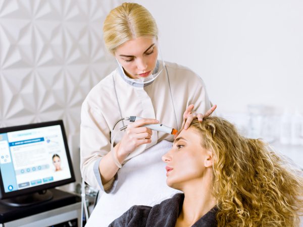 doctor cosmetologist doing hydrafacial procedure in modern cosmetology clinic